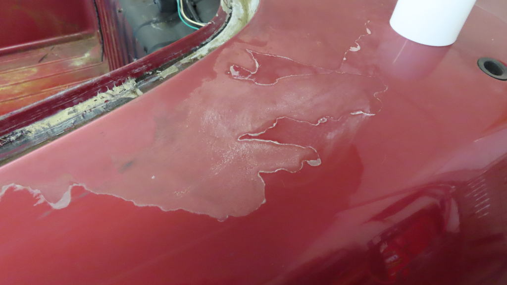 Peeling clear coat on a red car fender